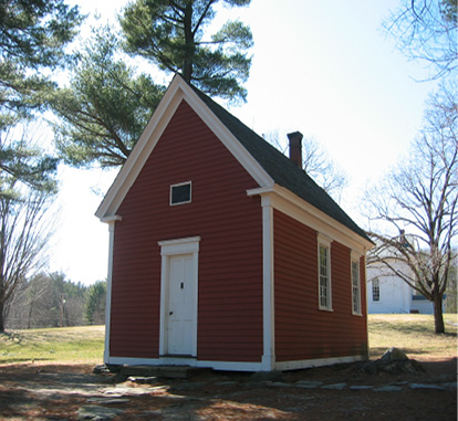 A very small likely 1 room school house with red panneling.