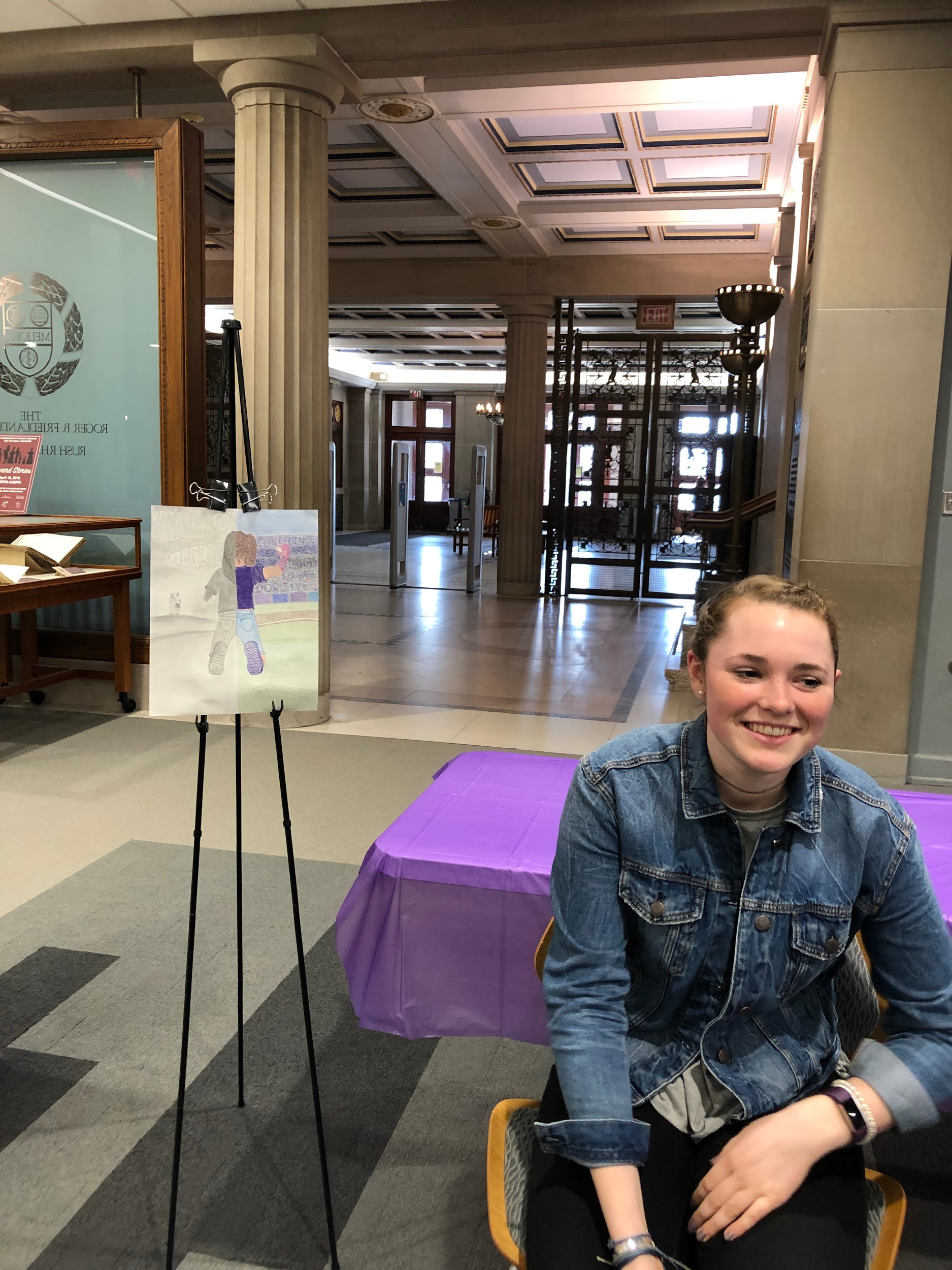 Maggie seated in front of her poster