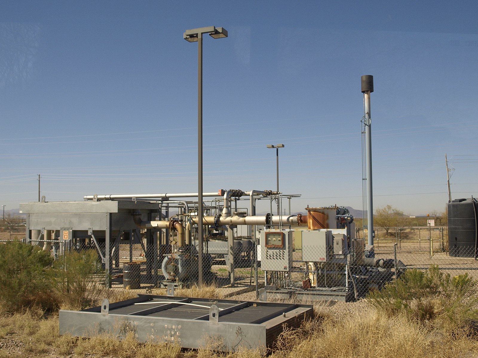 a group of machines and pipes in a grassy field