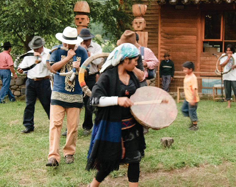 Photo of men and women dancing, beating drums.