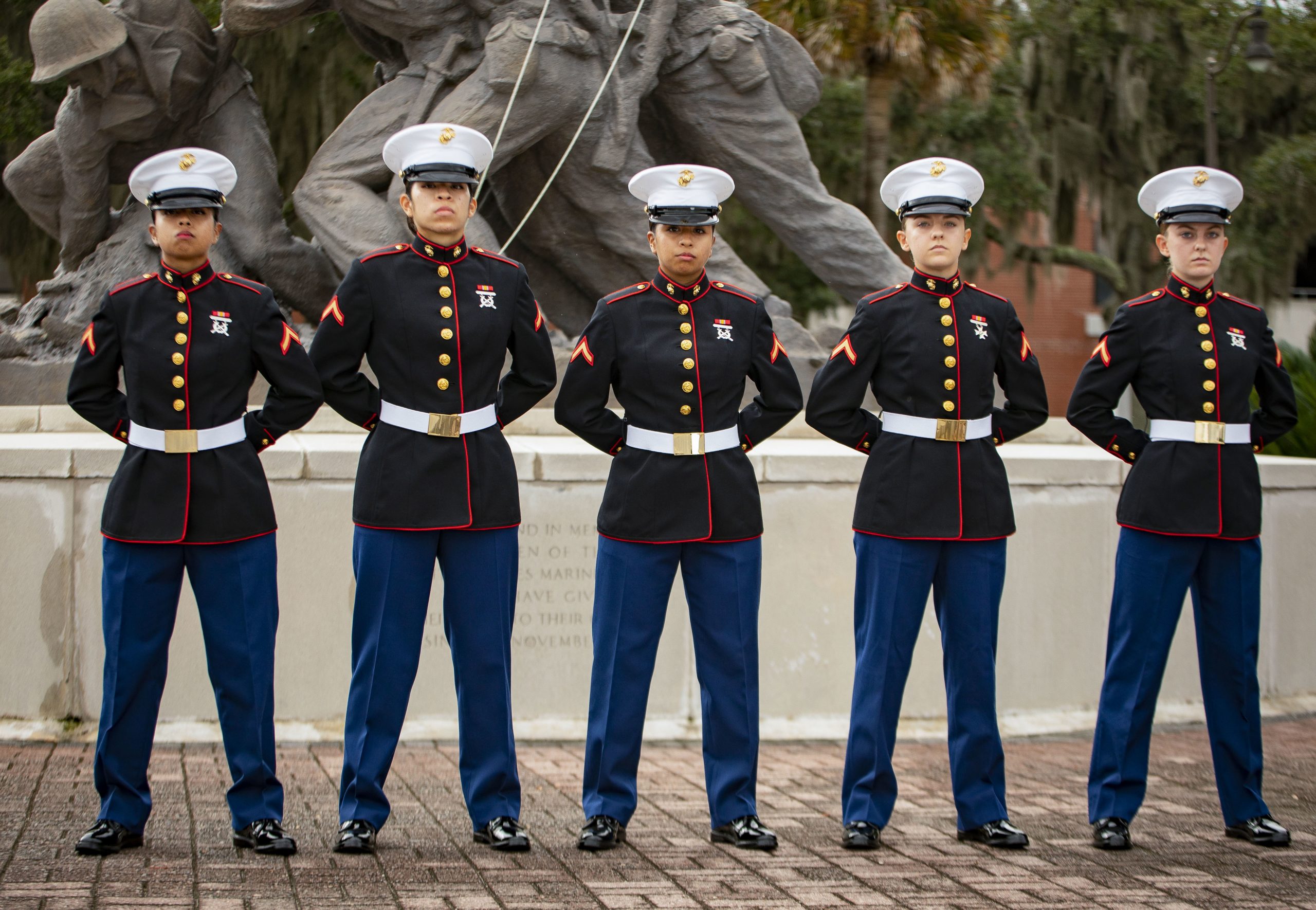 A line of five women in the Marine Corps, wearing generally masculine uniforms.