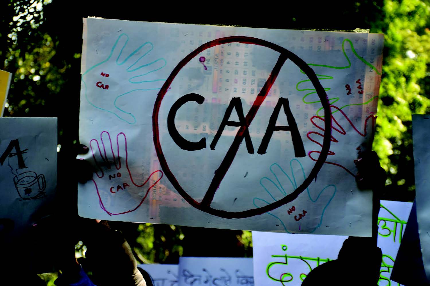 A figure holds up a sign that says "CAA" but crossed-out.