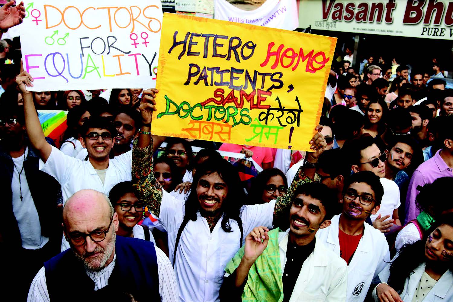 A crowd of people hold up signs; one says "Hetero Homo patients, same doctors."