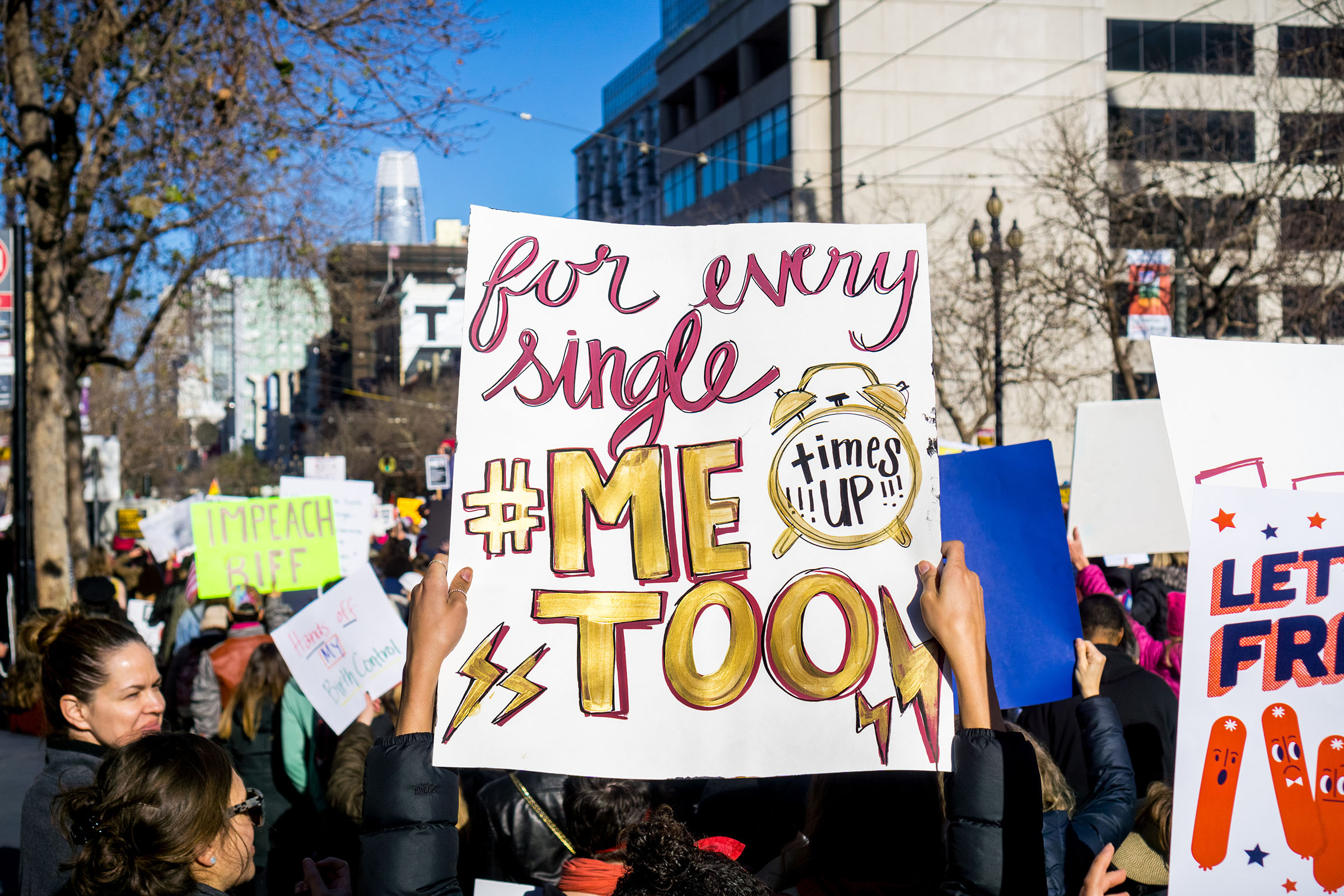 A person holds up a sign during a protest that says "For every single #MeToo time's up!"