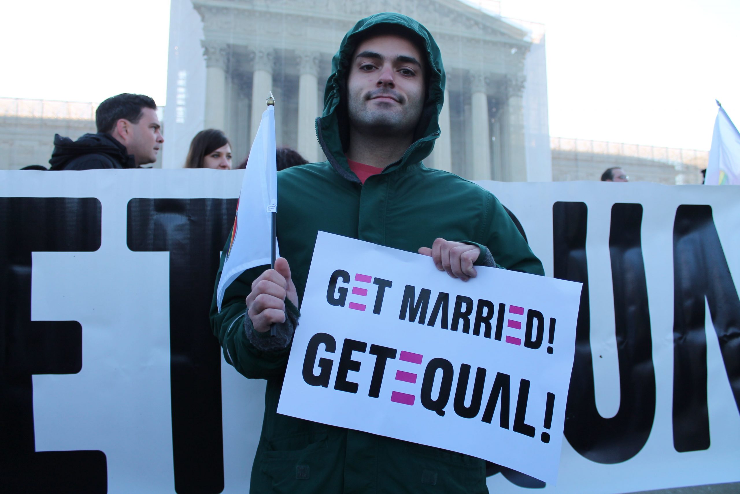 A person holds a sign that says "Get Married! Get Equal!"