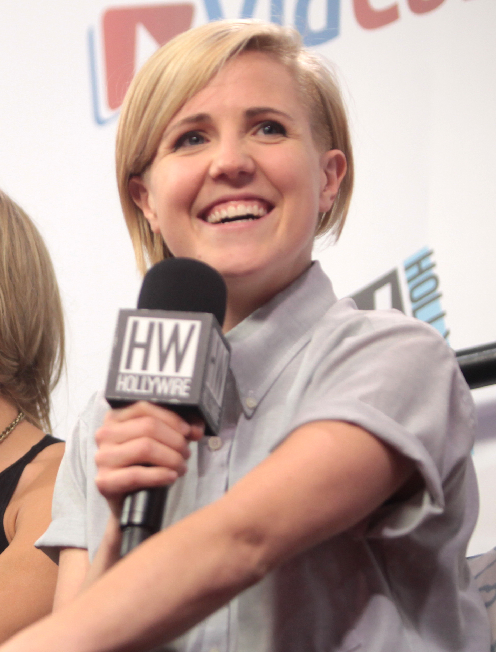 A woman holding a microphone smiles.