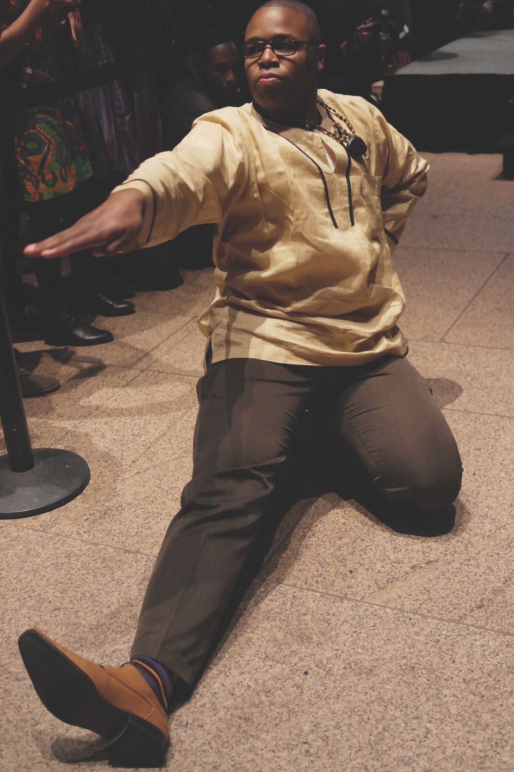 A dancer mid-pose on the floor with one leg out in front and the other tucked underneath.