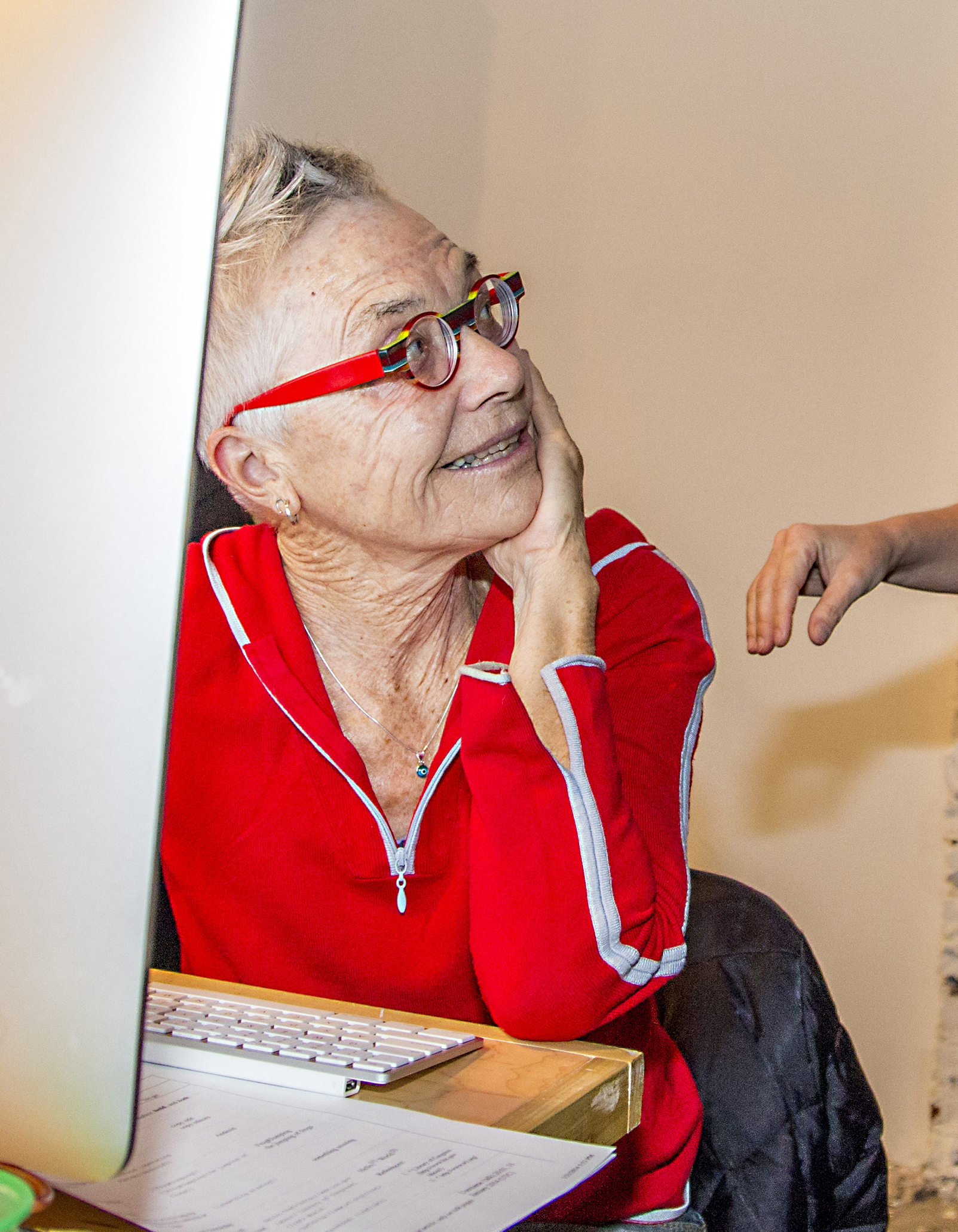 A woman looks up from a computer, smiling.