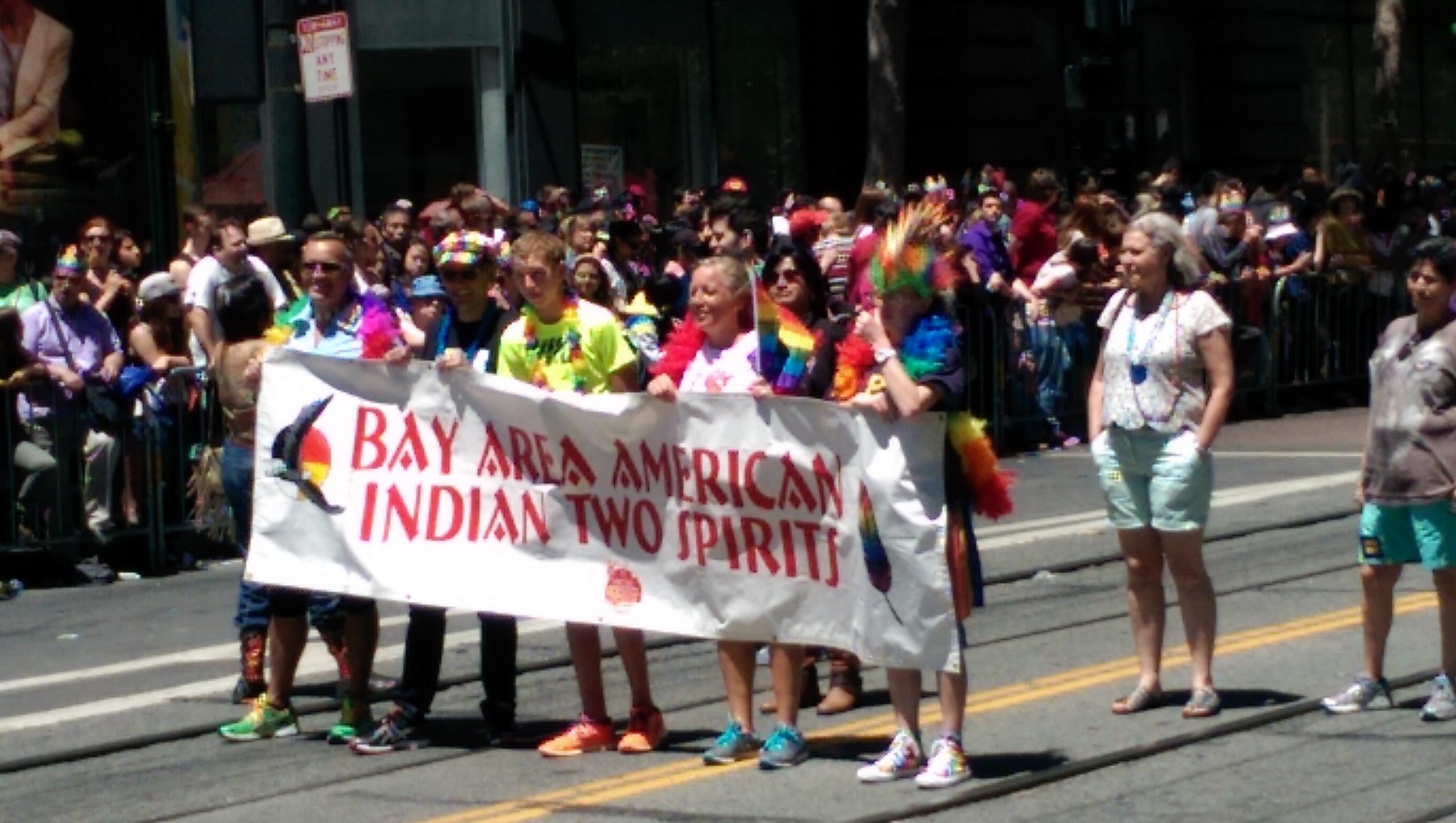 A line of people hold a sign that says "Bay Area American Indian Two Spirits."