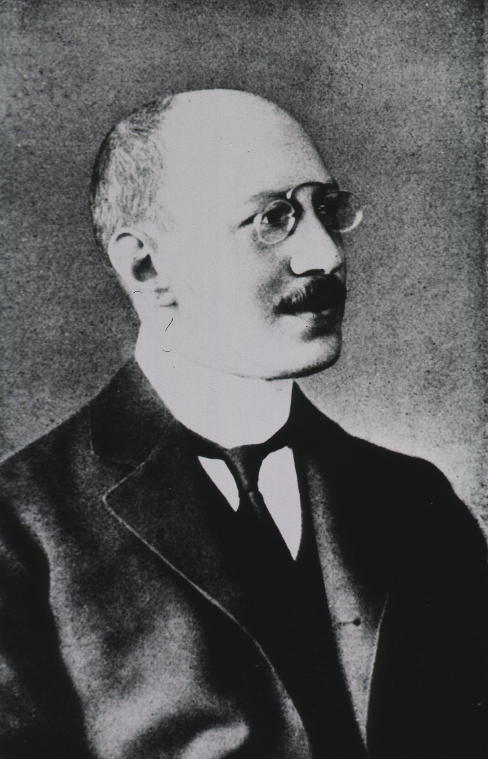 Old photograph of a man in a suit with glasses.