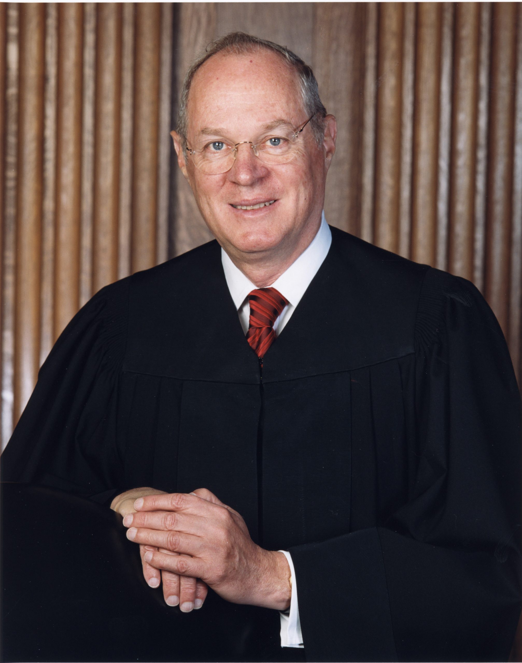 A man in a robe looks at the camera, smiling.