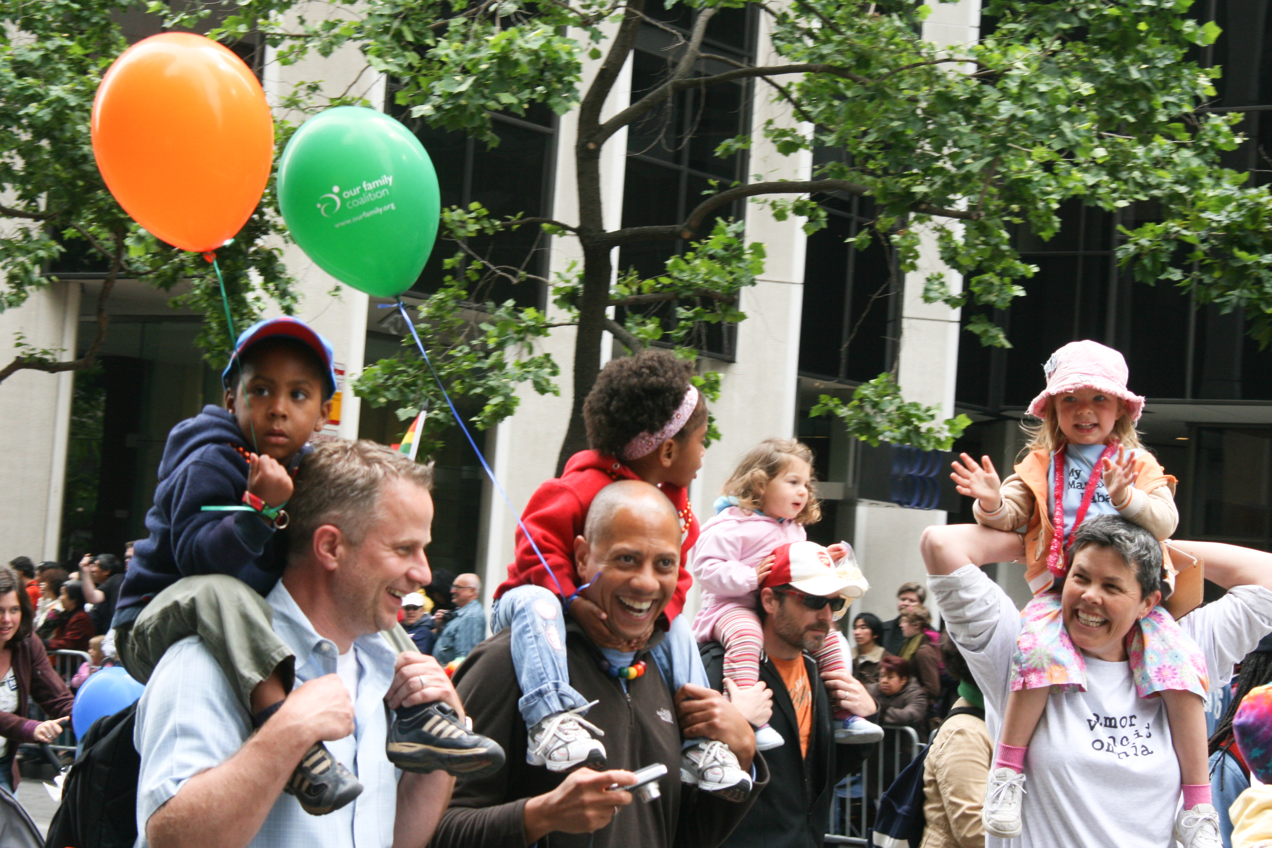 Parents hold their children on their shoulders.