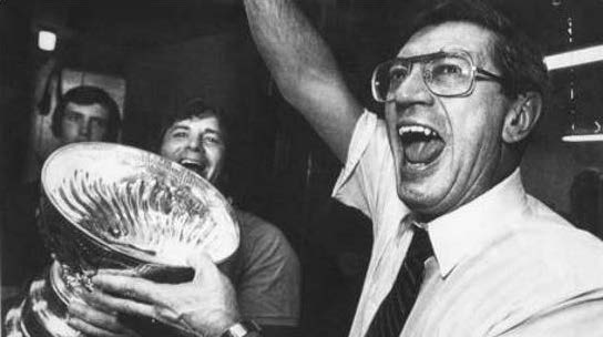 A photo of a man celebrating and holding a large silver cup.