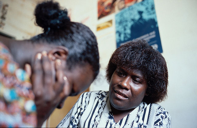 A person comforts another who is crying, covering their face with hands.