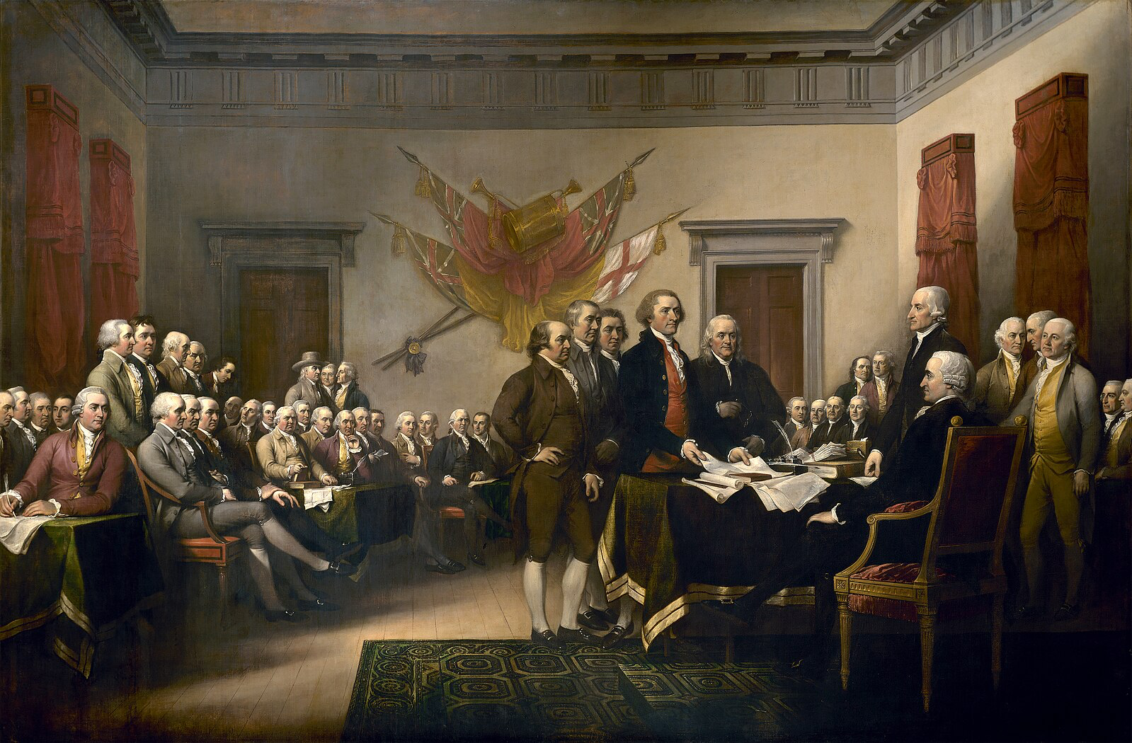 A painting depicting the signing of the Declaration of Independence: a formal assembly with men in 18th-century attire gathered around a table, discussing and signing a document.